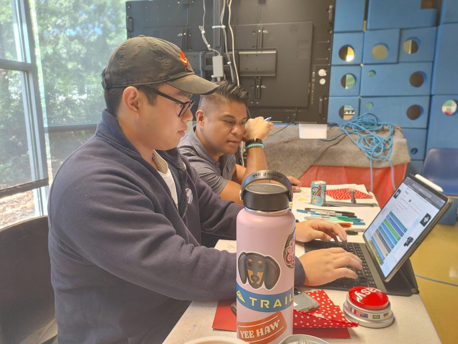 Shawn Liu and Sean Puno working together at a desk. 