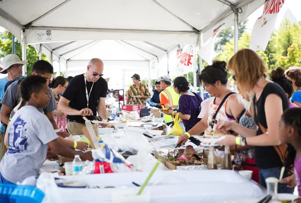 Group of people grabbing food from the table. 